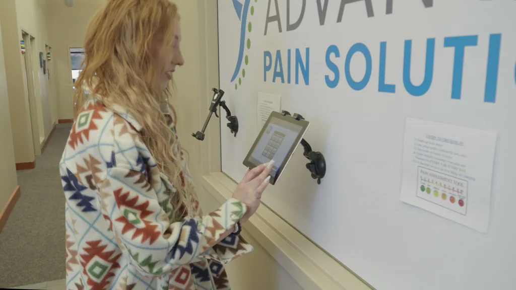 Check-in at the Advanced Pain Solutions tablet kiosk by the logo wall